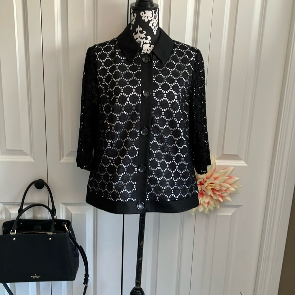 Black button front jacket w/ white lining showing through black geometric design